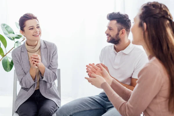 Femmes souriantes et homme assis et applaudissant pendant la séance de thérapie de groupe — Photo de stock