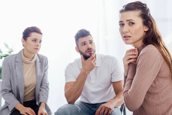 Femme bouleversée regardant la caméra pendant la séance de thérapie de groupe — Photo de stock