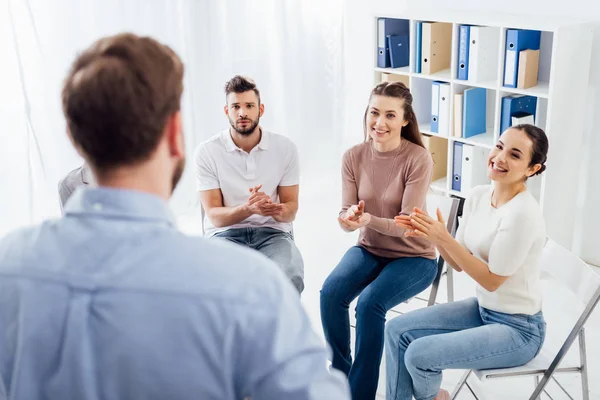 Persone sorridenti applaudono mentre guardano l'uomo durante la sessione di terapia di gruppo — Stock Photo