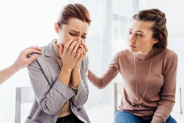 Mujer consolando a otra mujer llorando durante la reunión de terapia - foto de stock