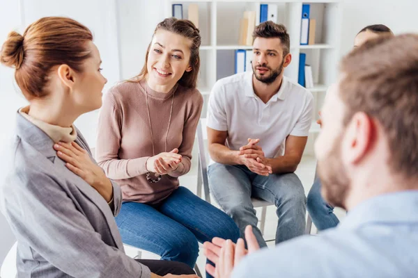 Grupo de personas sentadas en sillas y aplaudiendo durante la sesión de terapia - foto de stock