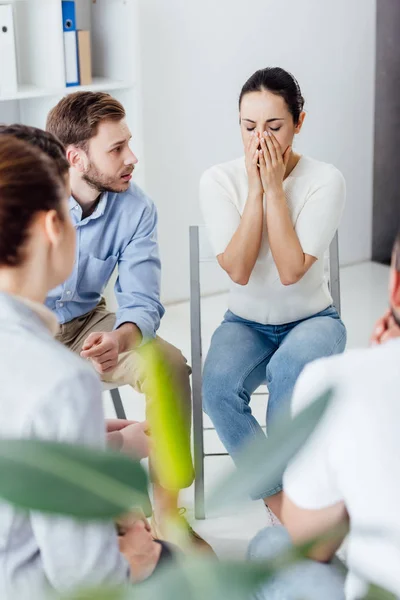 Selective focus of woman covering face and crying during group therapy meeting — Stock Photo