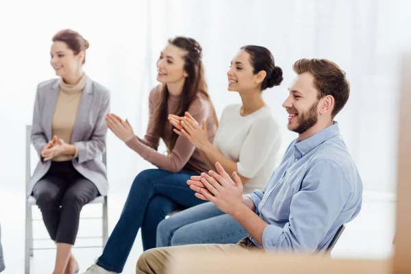 Lächelnde Gruppe von Menschen, die während der Sitzung der Selbsthilfegruppe sitzen und applaudieren — Stockfoto