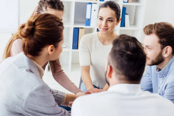 Personas sentadas apilándose las manos durante la sesión de terapia de grupo - foto de stock