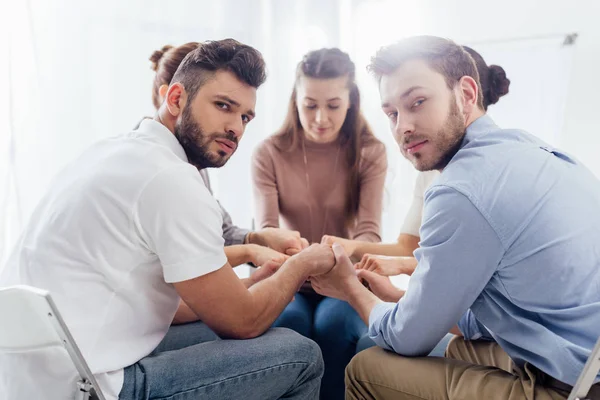 Selective focus of group of people sitting and stacking hands during therapy session — Stock Photo