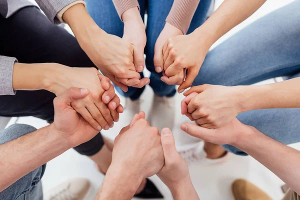 Vista parcial de personas cogidas de la mano durante la sesión de terapia de grupo - foto de stock