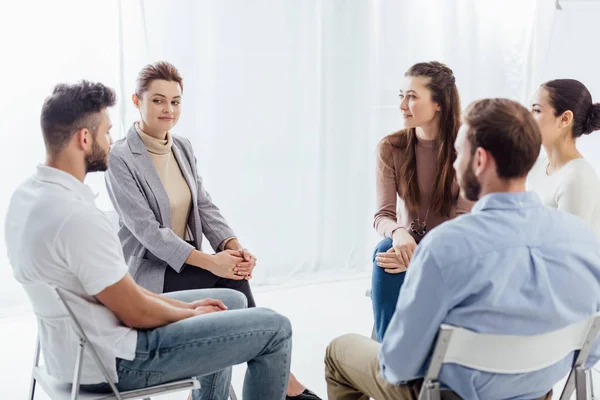 Personas sentadas en círculo durante la reunión de terapia de grupo de apoyo - foto de stock