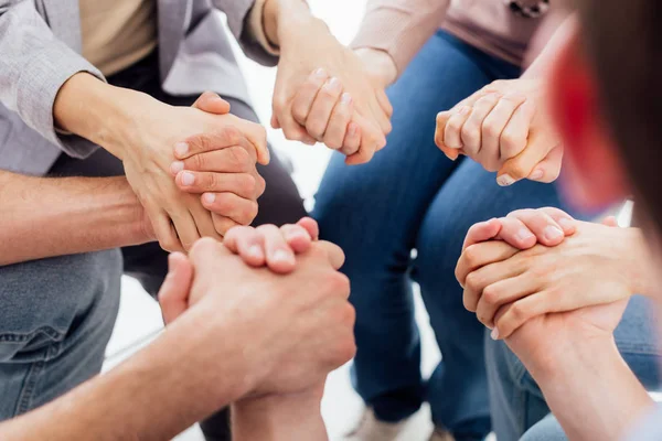 Vista recortada de personas cogidas de la mano durante la sesión de terapia de grupo — Stock Photo