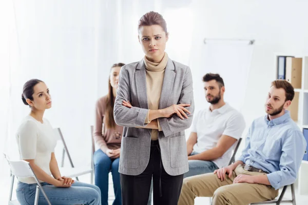 Frau blickt in die Kamera, während Menschen während einer Gruppentherapie auf Stühlen sitzen — Stockfoto