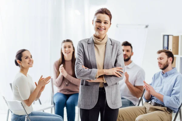 Smiling woman looking at camera while people sitting and applauding during group therapy session — Stock Photo