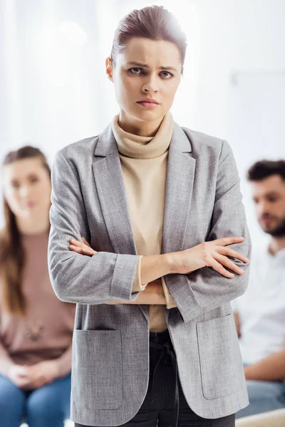 Traurige Frau in offizieller Kleidung blickt während einer Gruppentherapie in die Kamera — Stockfoto