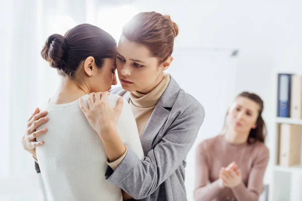 Selektiver Fokus der Frau, die während eines Therapietreffens eine andere Frau umarmt — Stockfoto