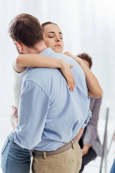 Enfoque selectivo de la mujer y el hombre abrazando durante la reunión de terapia - foto de stock