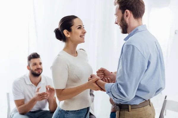 Beautiful smiling woman holding hands with man during group therapy session — Stock Photo