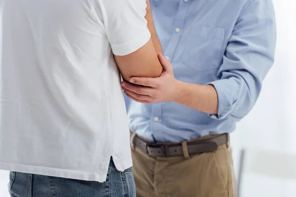 Visão cortada de homens consolando outro homem durante reunião de terapia — Fotografia de Stock