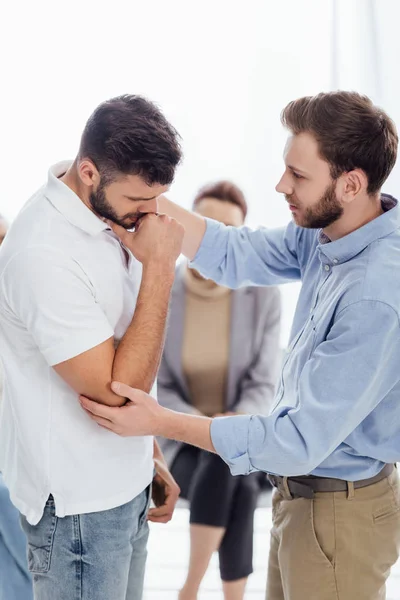 Selective focus of man consoling upset man during therapy meeting — Stock Photo