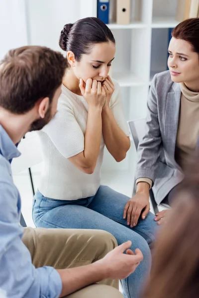 Selektiver Fokus der besorgten Frau, die während der Gruppentherapie den Mund mit den Händen bedeckt — Stockfoto