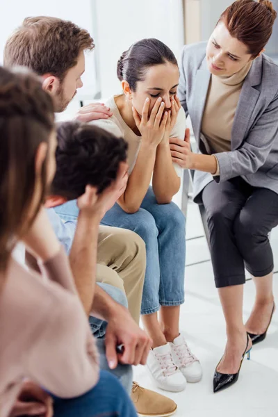 Селективное внимание женщины, покрывающей лицо и плачущей во время групповой терапии — стоковое фото