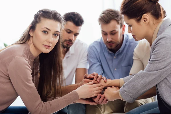 Gruppo di persone sedute e impilare le mani durante la sessione di terapia — Foto stock