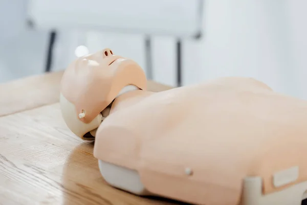 Enfoque selectivo del maniquí cpr para entrenamiento de primeros auxilios en mesa de madera - foto de stock