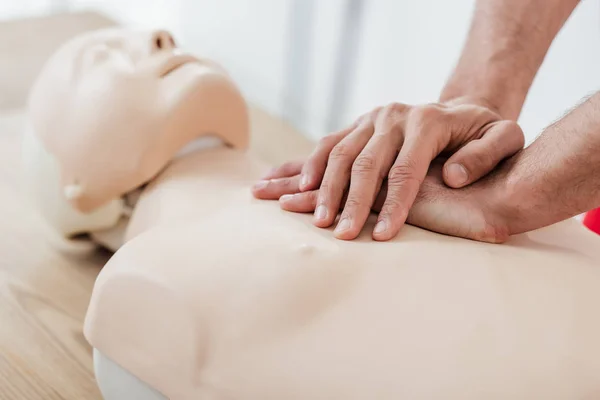 Vista ritagliata dell'uomo utilizzando la tecnica di compressione toracica sul manichino durante l'allenamento cpr — Foto stock