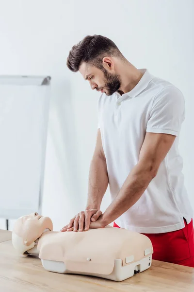 Homem bonito usando a técnica de compressão torácica no manequim durante o treinamento cpr — Fotografia de Stock