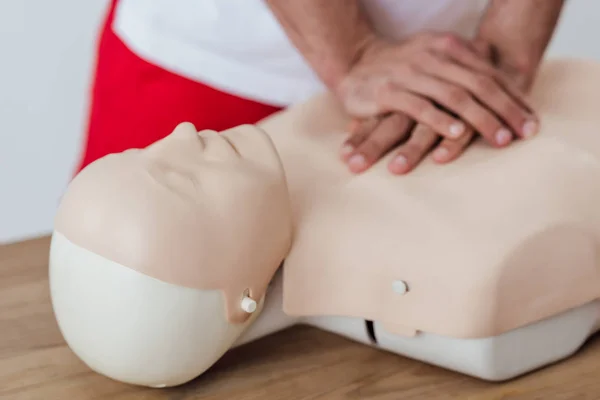 Обрезанный вид человека с помощью метода сжатия груди на манекен во время тренировки CPR — стоковое фото