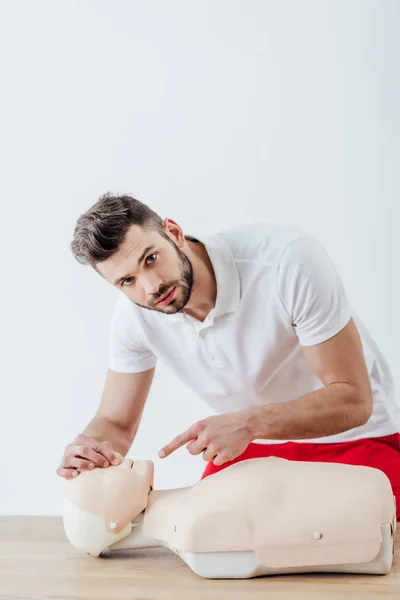 Mann schaut in Kamera und zeigt mit Finger auf Dummy beim CPR-Training — Stockfoto