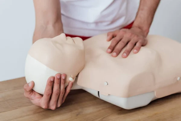 Teilansicht eines Mannes, der eine Attrappe hält, während er beim Erste-Hilfe-Training CPR übt — Stockfoto