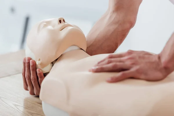 Teilansicht eines Mannes, der eine Attrappe hält, während er beim Erste-Hilfe-Training CPR übt — Stockfoto