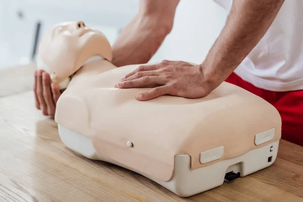 Cropped view of man holding dummy while practicing cpr during first aid training — Stock Photo