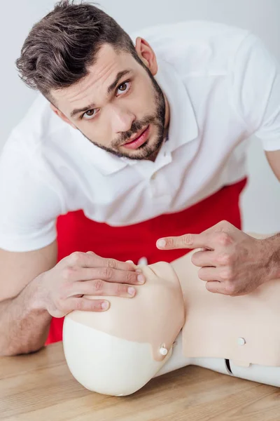 Schöner Mann schaut in die Kamera und zeigt mit dem Finger während des CPR-Trainings — Stockfoto