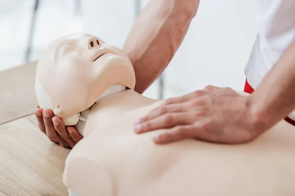 Vista recortada del hombre sosteniendo maniquí mientras practica cpr durante el entrenamiento de primeros auxilios - foto de stock