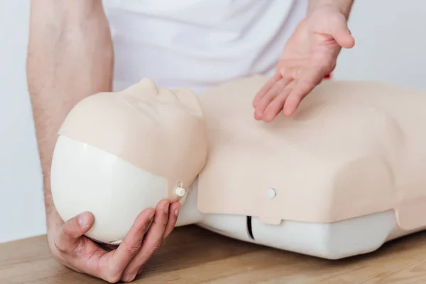 Cropped view of man holding dummy and gesturing while practicing cpr during first aid training — Stock Photo