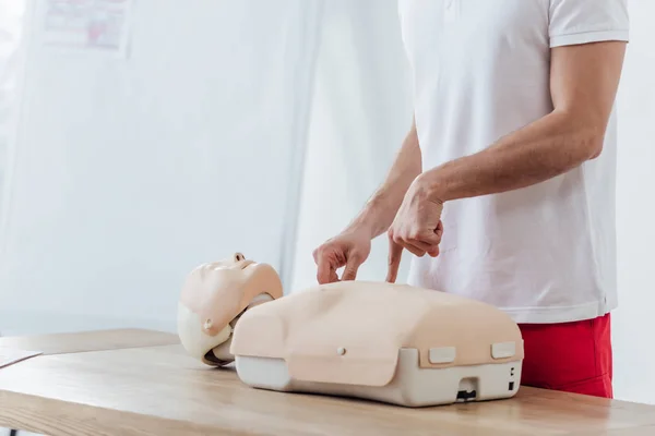 Cropped view of man pointing with finger at dummy while practicing cpr during first aid training — Stock Photo