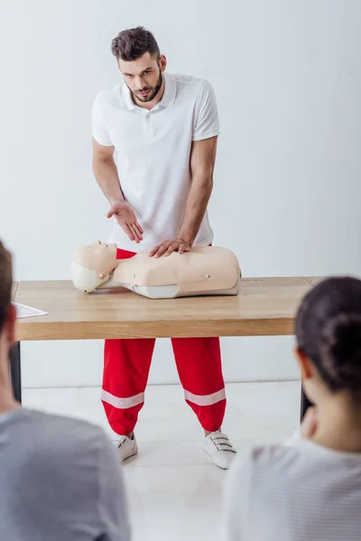 Enfoque selectivo de guapo instructor gesto durante el entrenamiento cpr - foto de stock