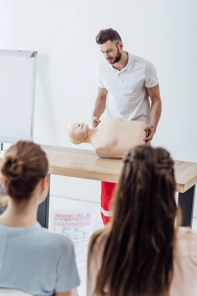 Selective focus of handsome instructor with cpr dummy during first aid training class — Stock Photo