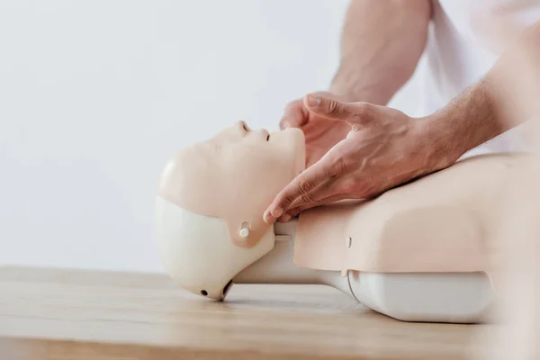 Cropped view of man holding dummy while practicing cpr during first aid training isolated on grey with copy space — Stock Photo