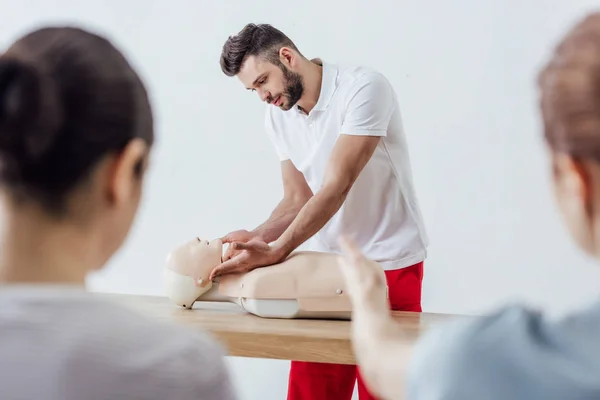 Selektiver Fokus eines gut aussehenden Ausbilders mit CPR-Attrappe während eines Erste-Hilfe-Kurses — Stockfoto