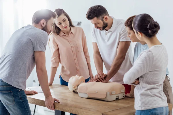 Group of people looking at man performing cpr on dummy during first aid training — Stock Photo