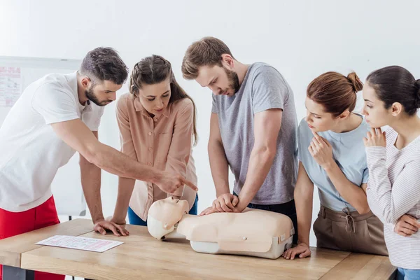 Grupo de pessoas com instrutor executando cpr no boneco durante o treinamento de primeiros socorros — Fotografia de Stock