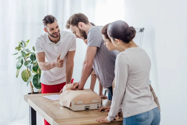 Grupo de pessoas com boneco cpr durante a aula de primeiros socorros — Fotografia de Stock