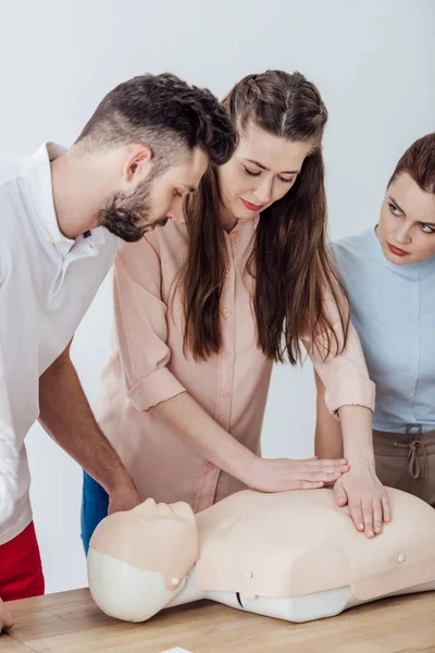 Belle femme effectuant la compression thoracique sur mannequin pendant le cours de formation cpr — Photo de stock