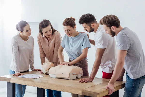 Group of smiling people performing cpr on dummy during first aid training — Stock Photo