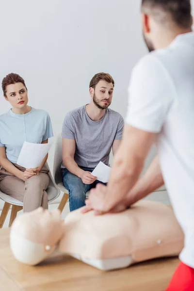 Rückansicht des Instruktors, der während des CPR-Trainings mit einer Gruppe von Personen Brustkompression auf einer Attrappe durchführt — Stockfoto