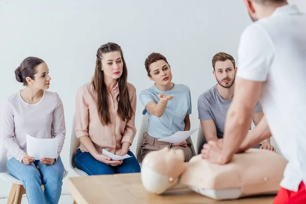 Back view of instructor performing cpr on dummy during first aid training with group of people — Stock Photo