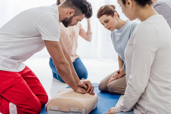 Instructor performing cpr on dummy during first aid training with group of people — Stock Photo