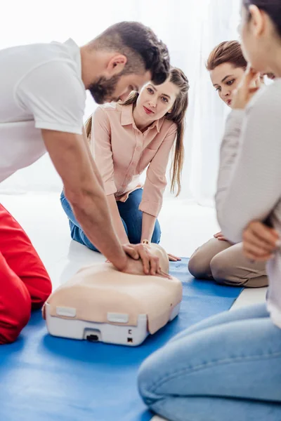 Selective focus of instructor performing cpr on dummy during first aid training with group of people — Stock Photo
