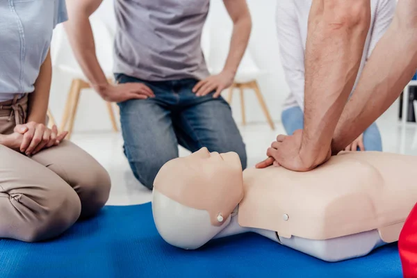 Vista recortada del grupo de personas durante el entrenamiento de primeros auxilios con maniquí - foto de stock