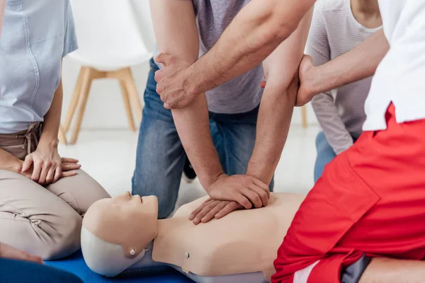 Vista recortada del grupo de personas durante el entrenamiento de primeros auxilios con maniquí - foto de stock